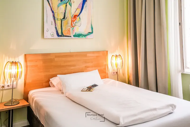 Classic Queen mit durchgehendem Bett, Holzkopfteil und farbenfrohem Kunstwerk an der Wand