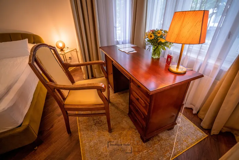 Antiker Schreibtisch mit Stehlampe und Blumen am Fenster eines Deluxe-Queen-Zimmers