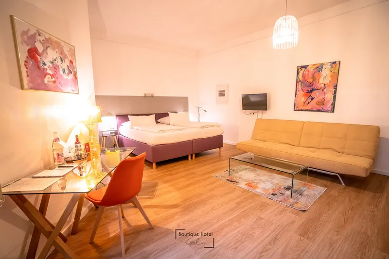 Salonzimmer mit großem Bett, Sofa, Glastisch mit Stühlen und Kunst an den Wänden